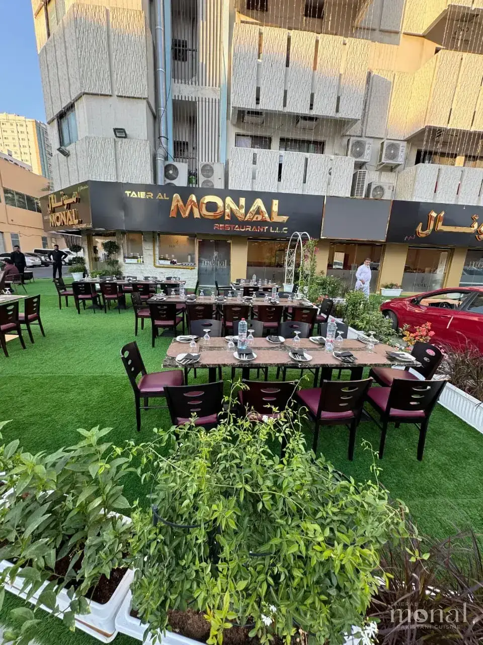 The Taier Al Monal frontage in Abu Shaghara, Sharjah, with outdoor garden seating below the gold sign